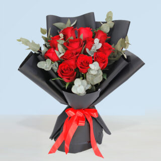 12-stem red roses with eucalyptus in black bouquet paper tied with red ribbon for Valentine's Day