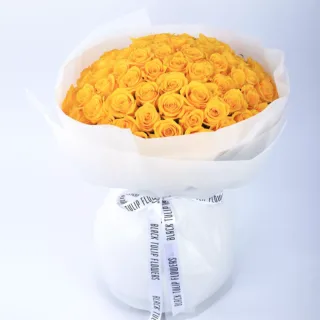 100 stems of vibrant yellow roses arranged in a white wrap, tied with a white ribbon.