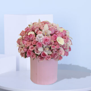 A large pink box filled with pink roses, white calla lilies, and white orchids.