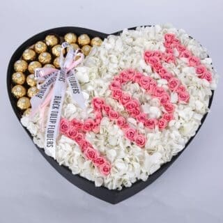 Heart-shaped box with chocolates and "Mom" spelled out with pink roses.
