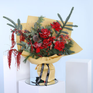 Christmas bouquet featuring red roses, fir branches, pine cones, and red berries