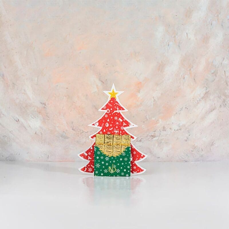 A festive chocolate shaped like a Christmas tree, adorned in vibrant red and golden colours, evoking holiday cheer.