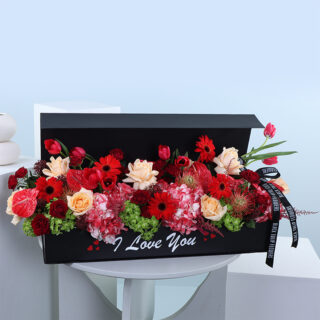 Red and orange flower arrangement in a black box with "I Love You" message.