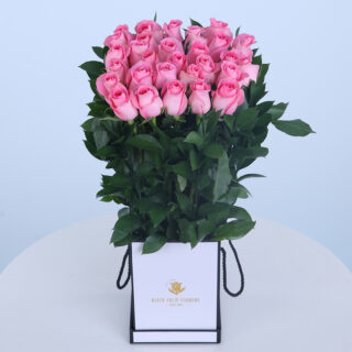 30 pink roses arranged elegantly in a decorative box with fresh green leaves.