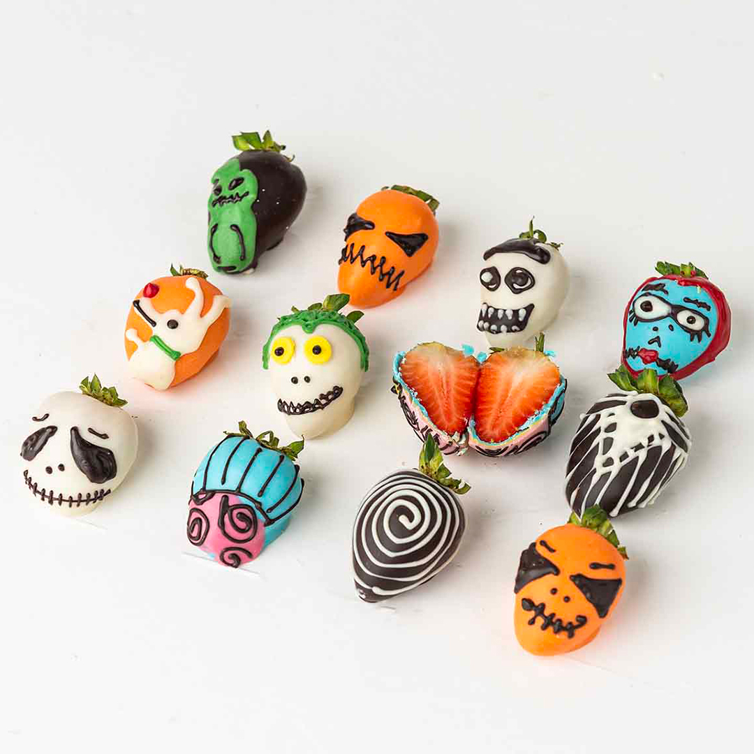 Twelve chocolate-covered strawberries decorated with Nightmare Before Christmas characters. The characters include Jack Skellington, Sally, Zero, and other iconic figures.