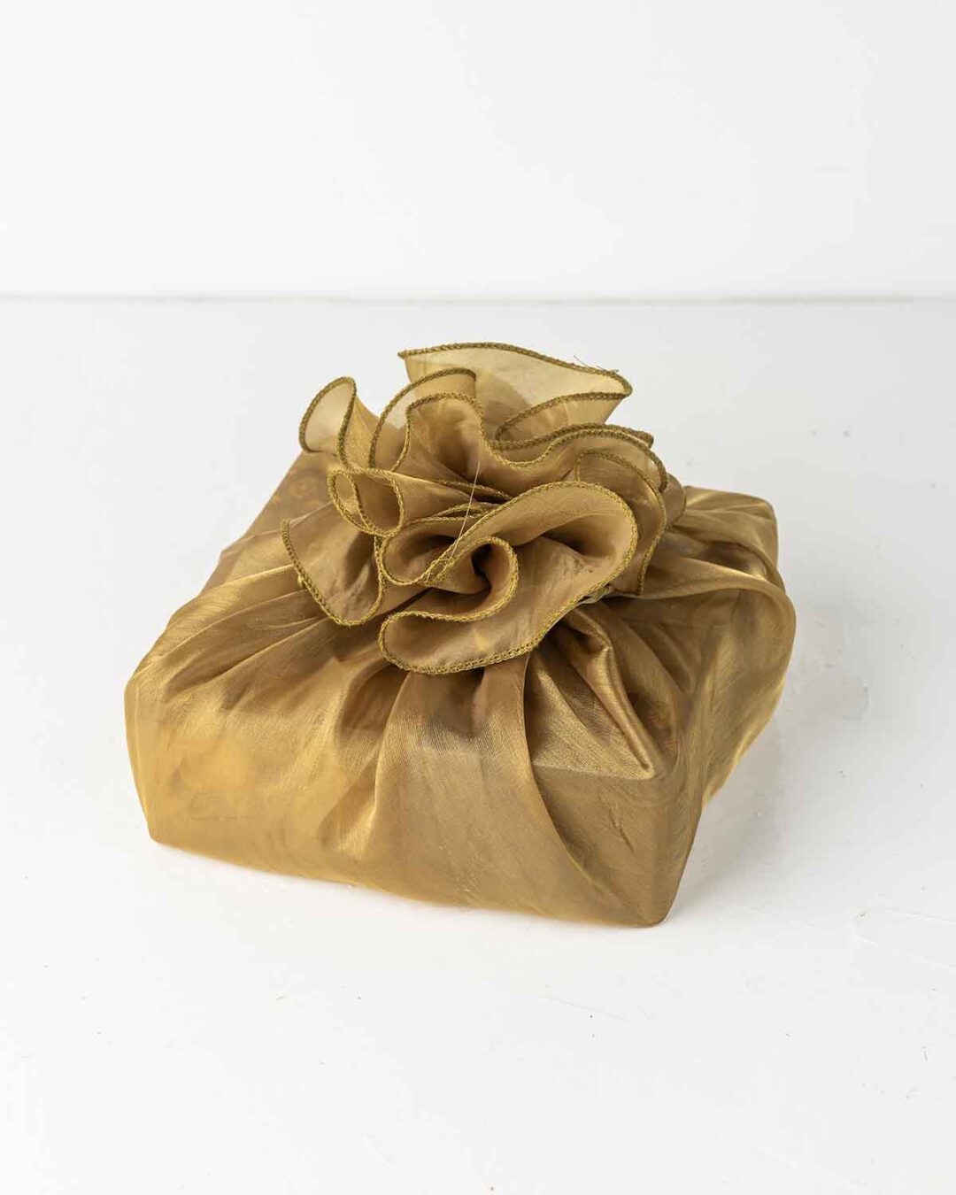 Four clear containers filled with different snacks arranged in a square basket lined with gold fabric. The containers hold various treats, including round, golden-brown snacks, white, round snacks, small, square brownies with nuts, and round, dark chocolate truffles.