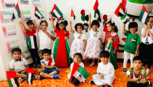 Celebrate UAE Flag Day with Creative Activities and Decorations 6 A group of students holding the flag of the United Arab Emirates, a horizontal tricolor of green, white, and black with a vertical red bar at the hoist