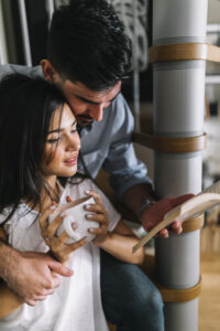 Valentine's Day Gift Ideas for Every Relationship ( 25 ideas) 6 A man sitting with his girlfriend, holding a coffee cup and looking at a book.