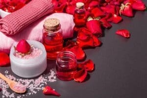 natural spa concept with fresh roses petals rose sea salt essential oil soft towels modern hard light dark shadow black stone concrete background copy space
