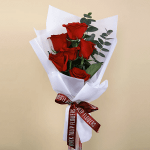A bouquet of six red roses wrapped in white paper with a maroon ribbon, tied with a tag that reads BLACK TULIP FLOWERS