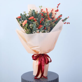 Christmas bouquet with red carnations, greenery, pinecones, and holly berries in a stylish arrangement.