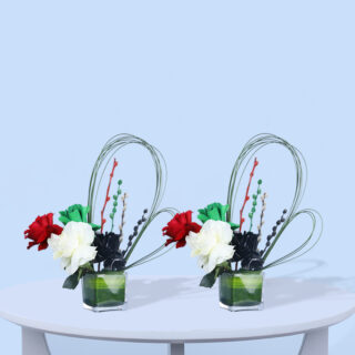 5 roses and lush greenery arranged in a clear glass vase