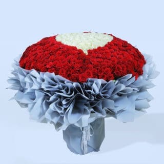 A large, luxurious bouquet of red roses with heart made of white roses at the centre.