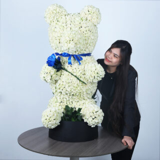 A large, cuddly white rose teddy bear