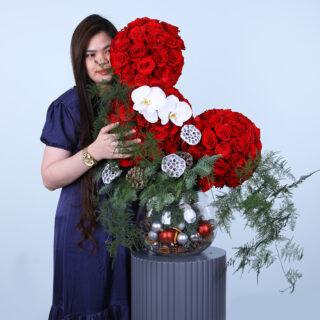 Festive fish bowl arrangement with 110 roses, orchids, and Christmas decorations.