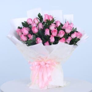 A bouquet of light pink roses wrapped in white paper with a pink ribbon.
