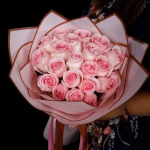 The bouquet consists of approximately 20 pink roses. The roses are a soft, light pink color and are arranged in a tight, rounded bunch.