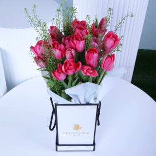 A luxurious gift box filled with elegant blush pink tulips, wrapped in white.