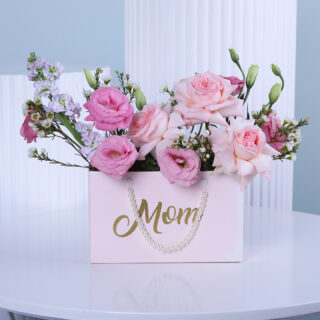 A beautifully curated pink gift bag filled with stunning pink and purple blooms, making a thoughtful and elegant gift.