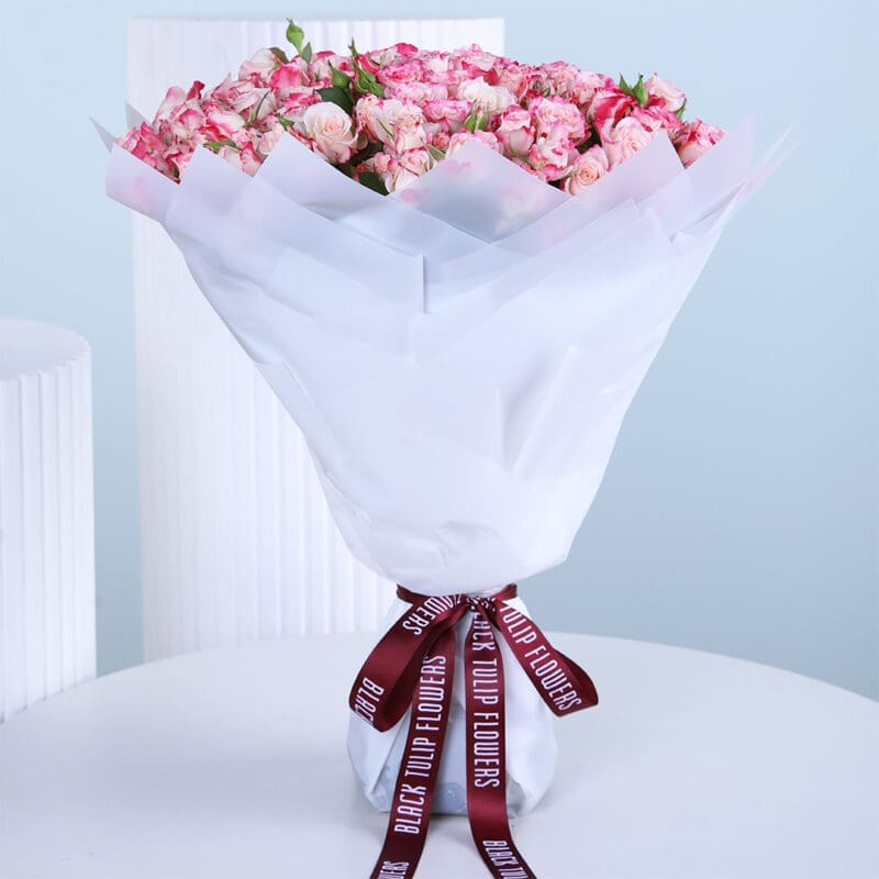 grand-baby-rose-bouquet A bouquet of fresh 50 pink baby roses wrapped elegantly in a white paper and tied with a black knot.