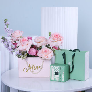 A delightful ‘Mom’ bag featuring pink and purple flowers, a luxurious green Patchi chocolate box, and an elegant gift bag.