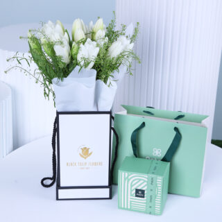 White tulips bouquet in a white wrap, presented with a gift box
