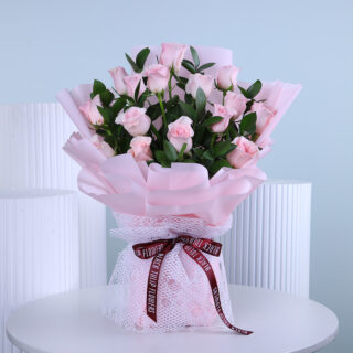 Light pink roses bouquet, elegantly wrapped in pink and tied with maroon ribbon.