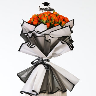 A full, vibrant bouquet of bright orange spray roses, wrapped in black and white with a "Congratulations" topper and a small graduation cap