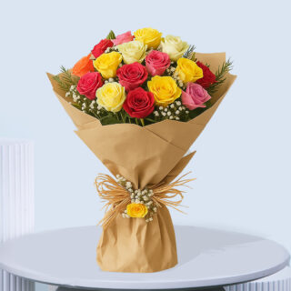 A vibrant bouquet of mixed garden roses in shades of red, yellow, pink, and orange with white baby's breath and green foliage, wrapped in brown paper and tied with a raffia bow and a small yellow rose.
