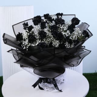 A vibrant bouquet of pink roses and white lilies wrapped in pink paper with a white ribbon presented on a white round table.