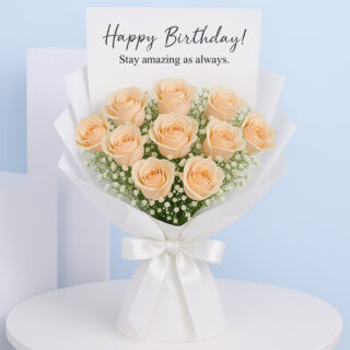 A beautiful bouquet of peach roses surrounded by white baby's breath, wrapped in white paper with a white ribbon, featuring a "Happy Birthday!" card.