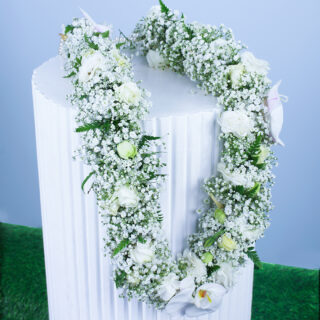 Graduation garland with white roses, orchids, baby’s breath, and pearl handles.