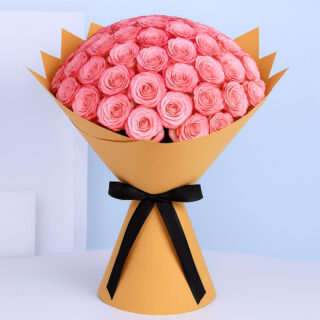 A large bouquet of fresh pink roses, tightly arranged and wrapped in brown and tied with a wide black ribbon.