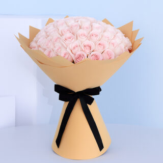 Bouquet of light pink roses wrapped in brown paper with a black ribbon.
