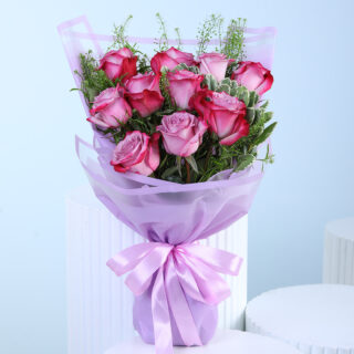 A bouquet of purple roses with green foliage, wrapped in translucent lavender paper and tied with a matching ribbon.
