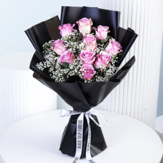 A luxurious bouquet featuring 10 purple roses and 5 stems of white gypsophila, stylishly wrapped in sleek black paper and tied with a white ribbon.
