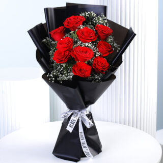 A bouquet of 10 vibrant red roses with white gypsophila (baby's breath) wrapped in black paper and tied with a black and white ribbon.