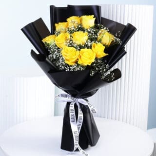 Bright yellow roses paired with delicate gypsophila, wrapped in deep black and finished with a chic monochrome ribbon.