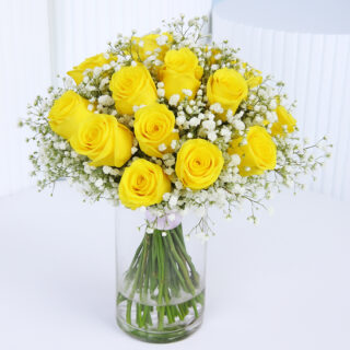 Vibrant yellow roses with white baby's breath arranged in a cylindrical glass vase.