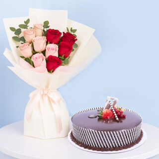A celebration combo featuring a bouquet of red and pink roses, a round chocolate cake with white stripes and strawberries on top..
