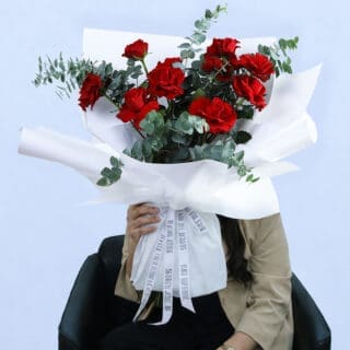 A bouquet of vibrant red roses and eucalyptus, ideal for romantic occasions or expressing care for someone special.