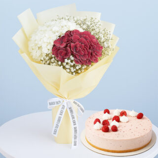 A gift combo featuring a beautiful bouquet of white and red hydrangeas with baby's breath, wrapped in cream and a light pink cake.