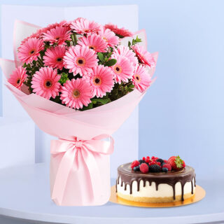 Flower Delivery Abu Dhabi 24 A vibrant bouquet of 20 pink Gerbera daisies with green leaves wrapped in pink and white stands next to a round cake.