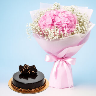 A large, vibrant bouquet of pink hydrangeas wrapped in pink paper with a pink ribbon and glossy chocolate truffle cake decorated with golden sprinkles and chocolate bits.
