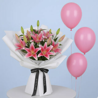 Flower Delivery Abu Dhabi 29 A vibrant pink lily bouquet with multiple blooming lilies and green buds, wrapped in white with a black branded ribbon and three pink balloons.