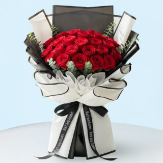Flower Delivery Abu Dhabi 37 A hand-tied bouquet of vibrant red roses arranged with green eucalyptus stems and wrapped in stylish black and white secured with a black ribbon.