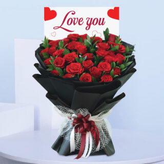 Love You bouquet featuring red roses hand-tied in black wrapping with a red and white ribbon and “Love You” card.