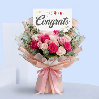 Pink roses congratulations bouquet with eucalyptus in blush pink wrap, tied with a satin ribbon and a “Congrats” card.