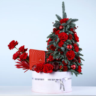 Christmas flower hamper with mini Christmas tree arrangement, red roses, Nobilis leaves, ornaments, and a Patchi 470g chocolate box.