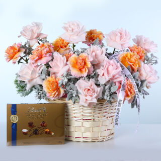 Basket of peach and pink Ecuador roses with Dusty Miller and Lindt chocolate box.
